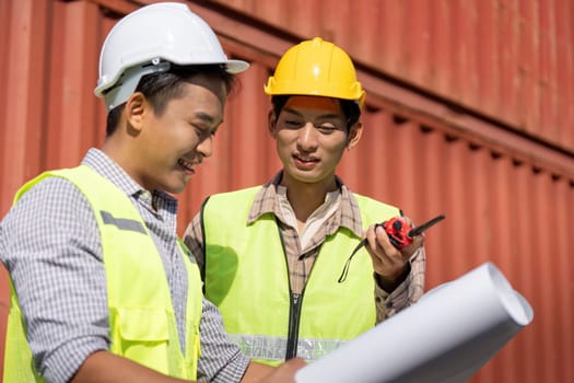 Engineers collaborate on construction logistics, using blueprints and a walkie-talkie for effective communication.