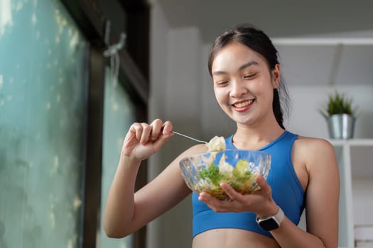 A joyful woman mixes a fresh salad, promoting healthy eating habits and nutrition in a vibrant indoor setting.