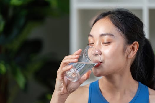 A healthy woman drinks water from a glass, showcasing the importance of hydration and wellness in daily life.