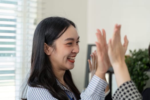 A joyful businesswoman shares a smile with colleagues after a successful handshake, showcasing teamwork and positive relationships in the workplace.
