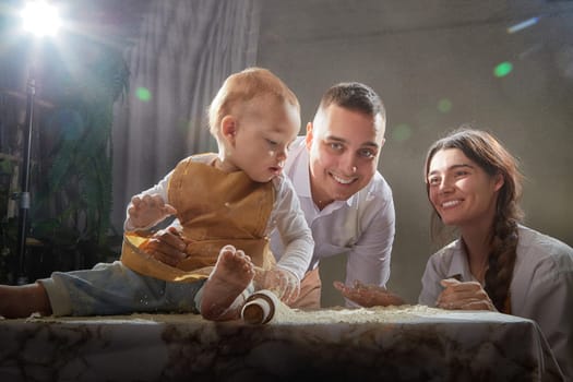 A family enjoys a fun cooking session, playfully covered in flour while engaging with their little ones in warm kitchen
