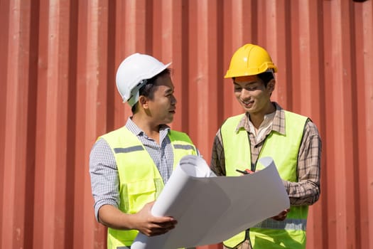 Two engineers analyze construction plans together, highlighting teamwork and effective communication in logistics.