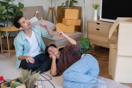 A happy gay couple enjoys moving into their new house, showcasing teamwork and love while unpacking and arranging their space.