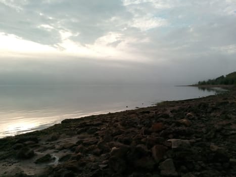 Awakening to the serene beauty of a quiet sunrise on the riverbank, where the gentle whispers of nature meet the stillness of the water.