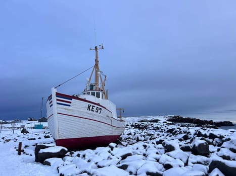 A boat waits for spring on a rocky beach of Keflavik in Iceland. High quality photo