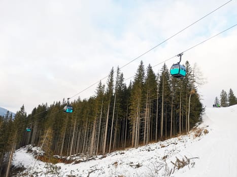 Closed cabins of the cable car at ski resort. Winter ski run. Cable car against the background of a pine forest