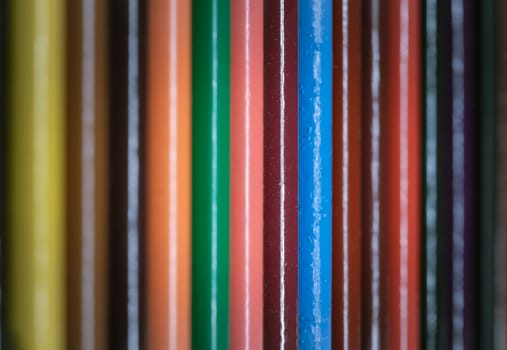 A perspective surface view of Multi colored pencils or wooden crayons to each other arranged in a neat row. The arrangement of the colors pencils creates a sense of unity. Pencils made of natural eco-friendly materials, Empty space for text, design and wallpaper, Selective focus.