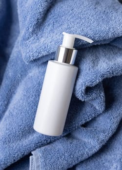 White blank one pump bottle on blue towel in bathroom closeuptop view, brand packaging mockup. Natural handmade cosmetic product - cream, lotion or soap for daily face or handcare, copy space