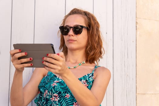 Portrait of a smiling young woman with sunglasses and digital tablet in hands.