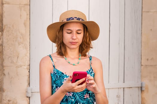 Portrait of a smiling young woman wearing a hat using a social media app