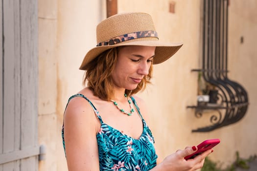 Portrait of a smiling young woman wearing a hat using a social media app