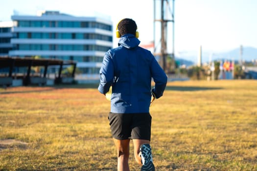 Young latin athlete with headphones training outdoors.