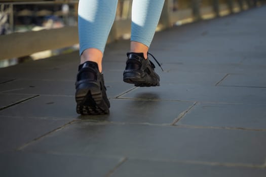 Feet of a sporty woman running through the streets of the city.