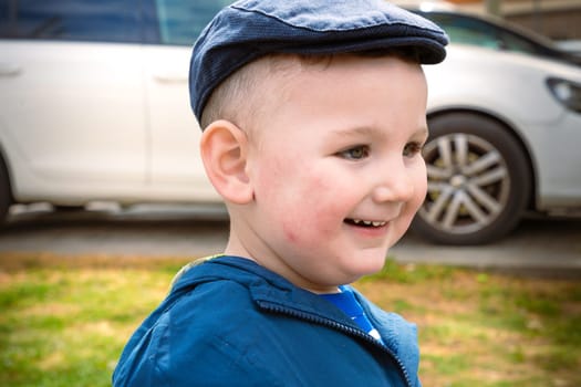 A happy little boy smiles enjoying an afternoon in the park. Portrait of boy in nature, park or outdoors.