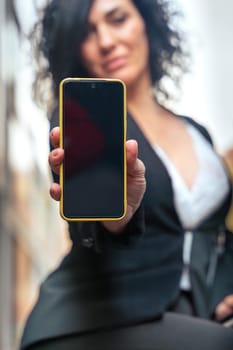 woman shows a smartphone with an empty screen for advertising or presentation, look at camera., smiling. Gadget Concept