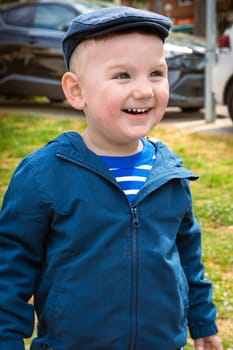 A happy little boy smiles enjoying an afternoon in the park. Portrait of boy in nature, park or outdoors.