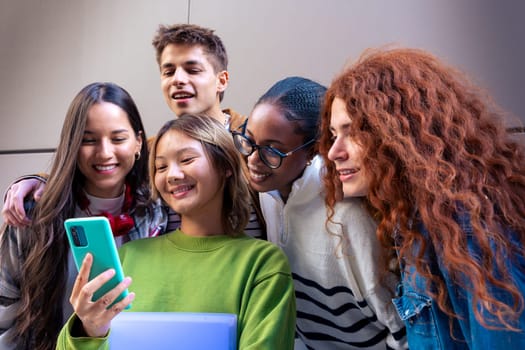 Five multiracial friends having fun using social media with their smartphone on the university campus. University life concept.