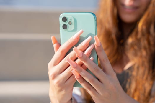 young woman hands using a smartphone with mobile device in a workplace - technology concept