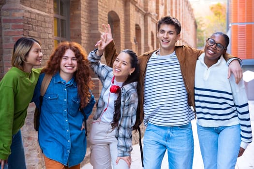 Multiracial group of students walking, laughing outdoors at the university. Young community of people having fun together.