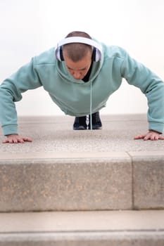 Concentrated young woman with sports headphones doing push-ups.