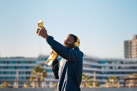 Cheerful young man taking a selfie on a cell phone and holding a sports bottle.
