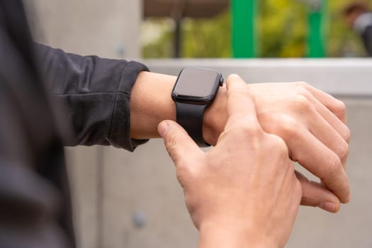 Partial view of a young athletic sportsman looking at a smart watch.