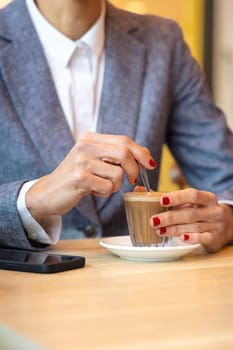 Business woman in a trendy cafe drinking coffee. with mobile on the table,beautiful caucasian.