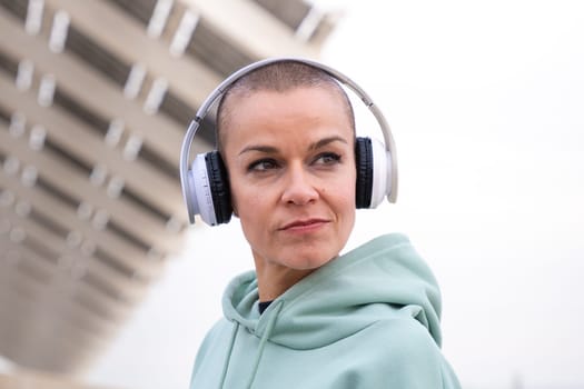 Portrait Fit woman smiling at camera with headphones on. Woman having fun during her morning workout.