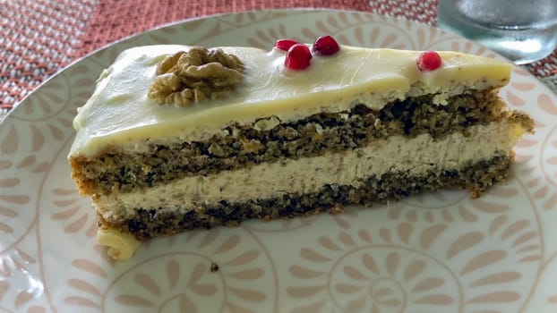 Slice of delicious Bulgarian walnut cake with white chocolate ganache, garnished with walnuts and red currants. A tasty treat, perfect for any occasion.