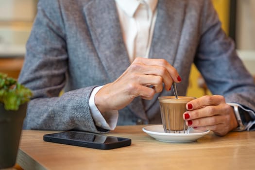 Business woman in a trendy cafe drinking coffee. Beautiful caucasian model with cell phone.