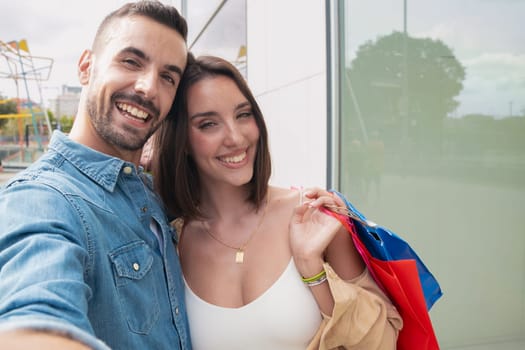 Boyfriend and girlfriend holding shopping bags and making a self portrait