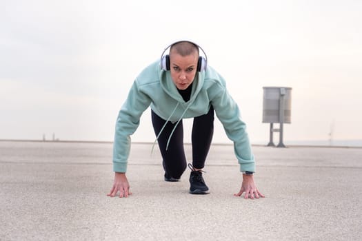 Concentrated young woman with sports headphones ready to start running.