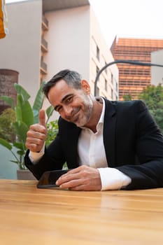 Middle-aged man sitting happily with thumbs up.