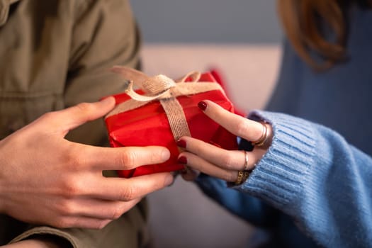 Unrecognizable young man and woman holding a red gift box.