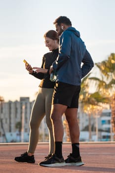 young couple using a social media app on smartphone while exercising outdoors.