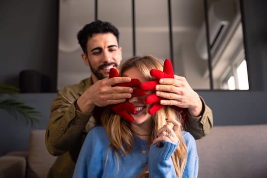 Smiling young man covers his girlfriend's eyes with a giant heart. Lovers