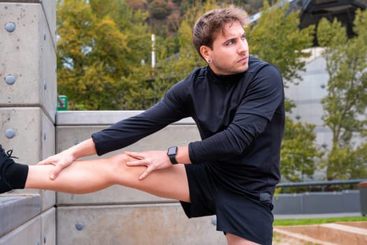 Young sportsman with concentrated sports watch stretching before training outdoors.