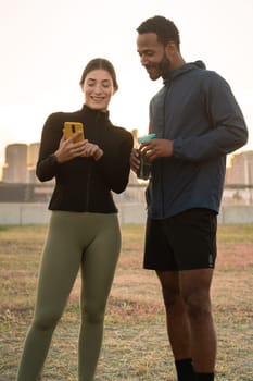 Vertical Photo of a young couple using a social media app on smartphone while exercising outdoors.