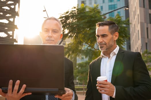 Two trusted business colleagues dressed in formal attire with a computer in hand observing the results of the work done