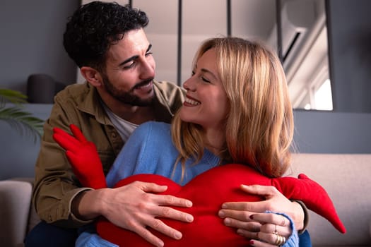Young couple look at each other lovingly smiling with a giant heart. Valentine's Day.