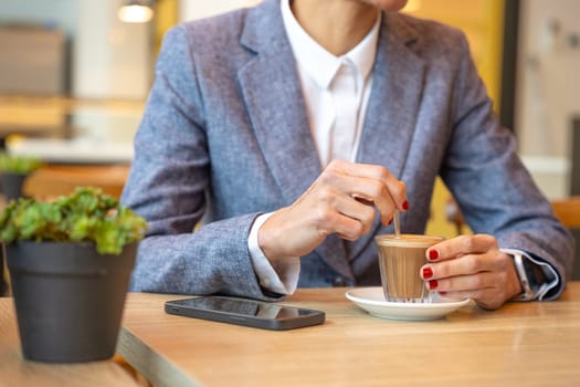 Business woman in a trendy cafe drinking coffee. with mobile on the table,beautiful caucasian.