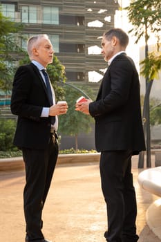 Portrait of two trusted business colleagues dressed in formal suit chatting together outside the workplace during work meeting.