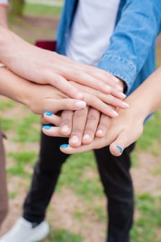 Happy young multiethnic students stacking hands in the city