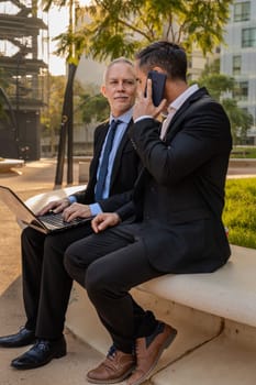 Two trusted business colleagues dressed in formal attire with a computer in hand observing the results of the work done.Vertical