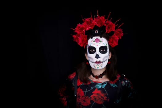 Woman dressed as a Mexican Catrina with a crown of red and black flowers