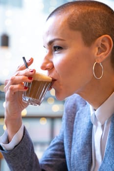 Businesswoman in a trendy cafe drinking coffee. Beautiful Caucasian Model Reflections of the windows.