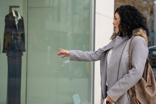 Woman shopping in the mall pointing new clothes at the window, showing a good discount price offer.