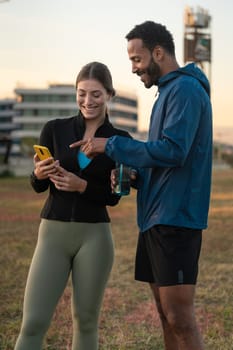 Vertical Photo of a young couple using a social media app on smartphone while exercising outdoors.