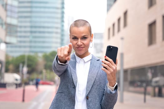 Confident middle adult pointing finger to front of logo. Smiling young woman pointing finger towards camera.