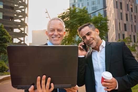 Two trusted business colleagues dressed in formal attire with a computer in hand observing the results of the work done